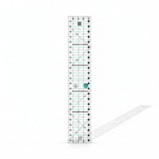 Creative Grids Quick Trim Two 4.5-inch by 24.5-inch long acrylic ruler laid across a folded bolt of fabric.