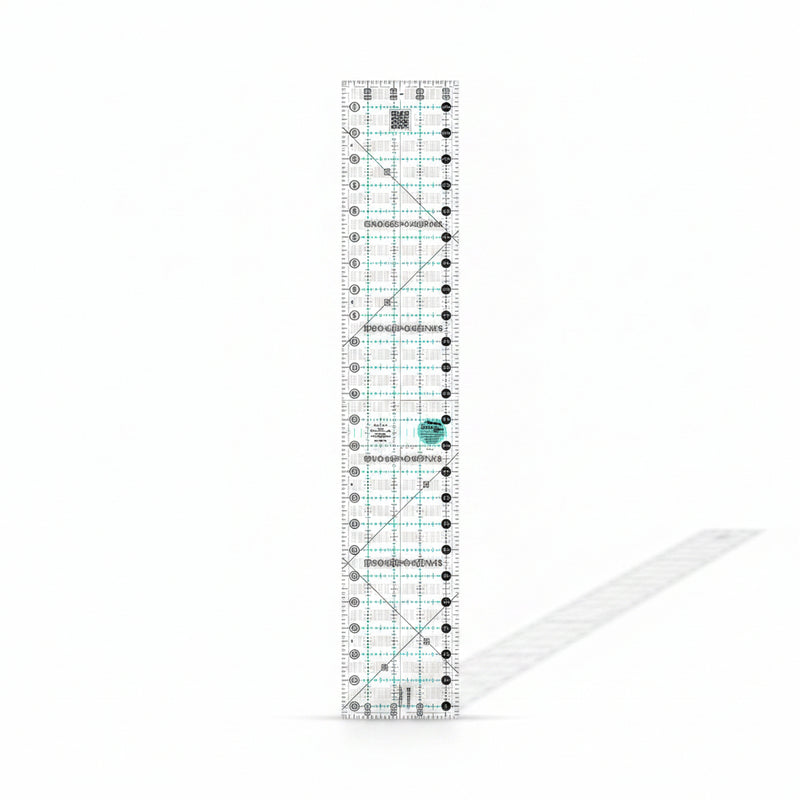Creative Grids Quick Trim Two 4.5-inch by 24.5-inch long acrylic ruler laid across a folded bolt of fabric.