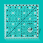 Creative Grids Itty-Bitty Eights 6-inch by 6-inch square quilting ruler sitting over a geometric patchwork block center.