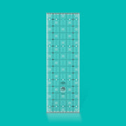 Creative Grids Charming Itty-Bitty Eights 5-inch by 15-inch rectangle quilting ruler sitting over a charm pack fabric layout.