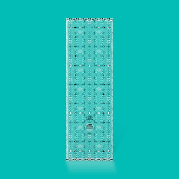 Creative Grids Charming Itty-Bitty Eights 5-inch by 15-inch rectangle quilting ruler sitting over a charm pack fabric layout.