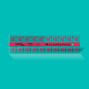 Creative Grids I Love My Quilt Friends 2.5-inch by 10-inch rectangle ruler with pink accents laid over jelly roll fabric strips.