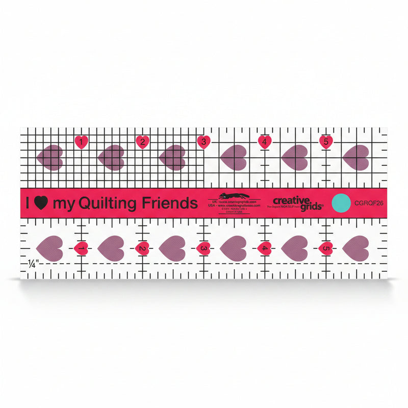 Creative Grids I Love My Quilt Friends Mini 2.5-inch by 6-inch rectangle ruler with pink accents laid over a small patchwork block.