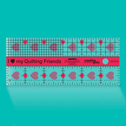 Creative Grids I Love My Quilt Friends Mini 2.5-inch by 6-inch rectangle ruler with pink accents laid over a small patchwork block.