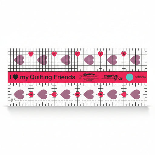 Creative Grids I Love My Quilt Friends Mini 2.5-inch by 6-inch rectangle ruler with pink accents laid over a small patchwork block.