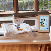 A close-up of a finished Disney character embroidery design on fabric next to the Brother Stellaire XJ2 sewing arm