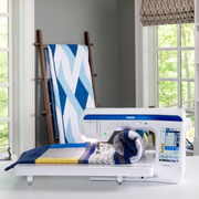 brother-innov-is-bq3100-sewing-machine-with-rolled-blue-and-grey-quilt-on-extension-table-in-craft-room