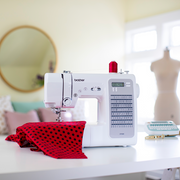 brother-cp100x-computerized-sewing-machine-lifestyle-view-on-white-table-with-red-and-black-polka-dot-fabric