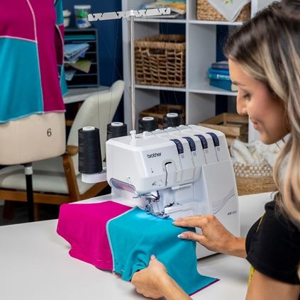 brother-air1800-air-serger-angled-front-view-showing-a-woman-feeding-pink-and-teal-fabric-into-the-machine