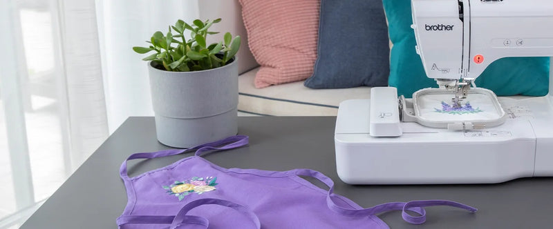 brother-pe545-embroidery-machine-on-table-next-to-finished-purple-apron-with-floral-embroidery