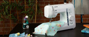 brother-pacesetter-ps100-sewing-machine-with-floral-light-blue-fabric-on-dark-table-front-view