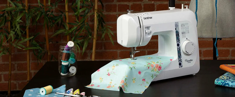 brother-pacesetter-ps100-sewing-machine-with-floral-light-blue-fabric-on-dark-table-front-view