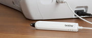 close-up-white-brother-ultrabuster-stylus-pen-resting-on-wooden-table-connected-via-cord-to-machine-base