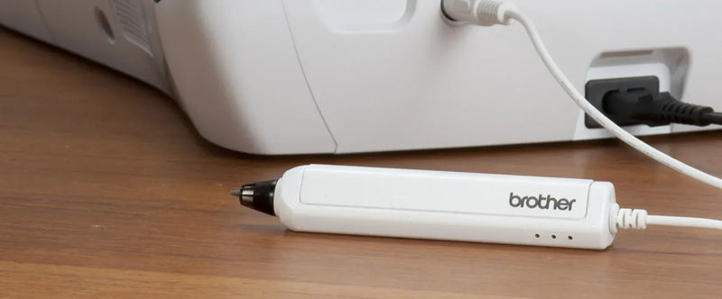 close-up-white-brother-ultrabuster-stylus-pen-resting-on-wooden-table-connected-via-cord-to-machine-base