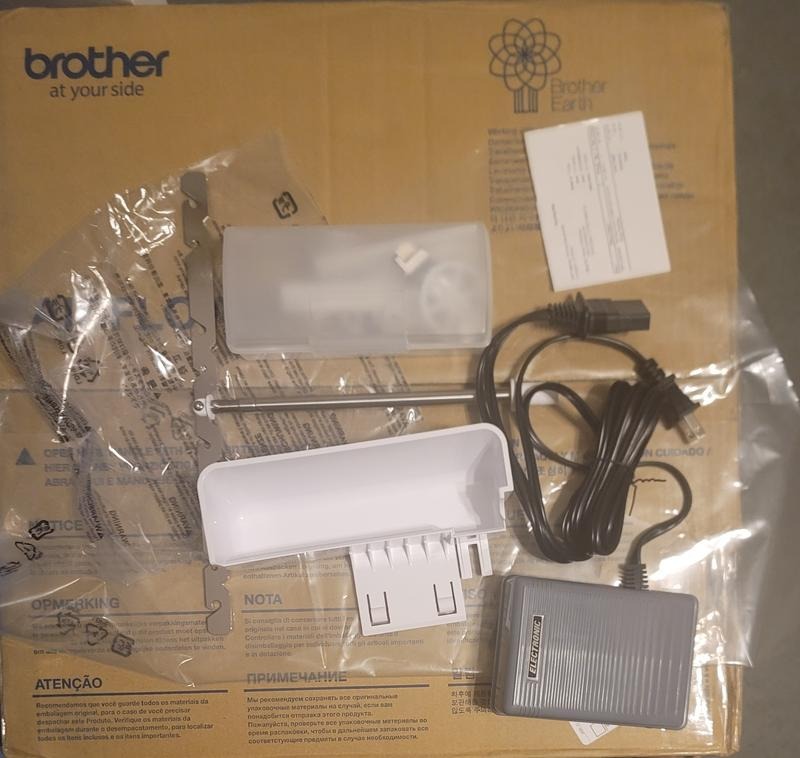 overhead-view-brother-airflow-3000-air-serger-unboxing-accessories-including-foot-controller-and-power-cord-over-cardboard-box