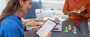 woman-using-stylus-on-tablet-next-to-brother-lb5500m-marvel-sewing-and-embroidery-machine-with-avengers-faceplate