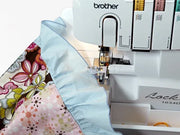brother-lock-1034d-serger-overhead-view-showing-light-blue-ruffled-fabric-and-floral-pattern-under-the-presser-foot
