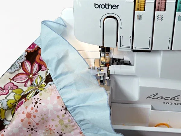 brother-lock-1034d-serger-overhead-view-showing-light-blue-ruffled-fabric-and-floral-pattern-under-the-presser-foot