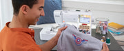 smiling-man-holding-grey-apparel-with-custom-captain-america-shield-embroidery-next-to-brother-lb5500m-marvel-machine