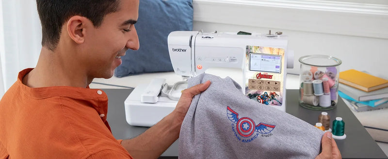 smiling-man-holding-grey-apparel-with-custom-captain-america-shield-embroidery-next-to-brother-lb5500m-marvel-machine