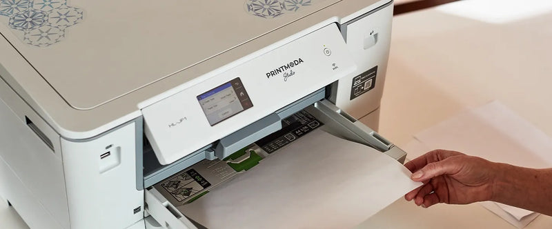 close-up-user-hand-loading-printable-fabric-sheet-into-lower-tray-of-brother-printmoda-studio-fabric-printer-hl-jf1