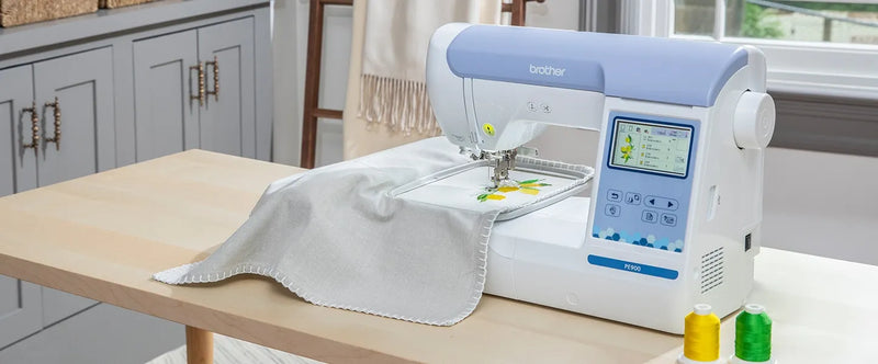brother-pe900-embroidery-machine-on-wooden-table-stitching-lemon-pattern-next-to-thread-spools