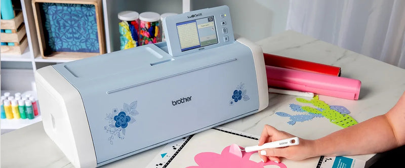 close-up-user-hand-weeding-pink-floral-vinyl-cutout-next-to-brother-scanncut-dx-innov-is-edition-sdx325-machine