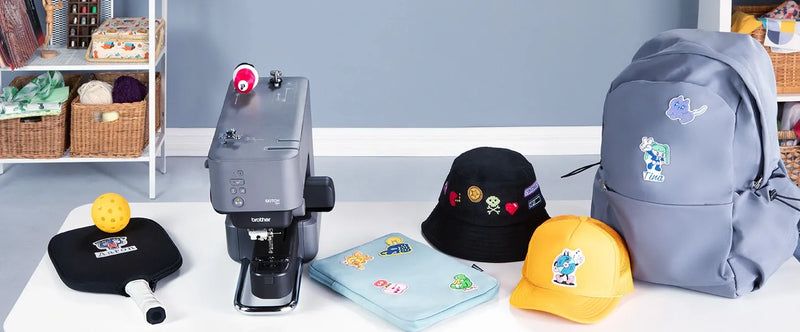brother-skitch-pp1-single-needle-embroidery-machine-on-table-surrounded-by-custom-embroidered-hats-caps-and-backpack