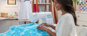 lifestyle-view-of-woman-sewing-blue-frozen-olaf-fabric-with-brother-innov-is-ns1850d-combo-sewing-embroidery-machine