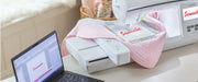 laptop-running-embroidery-software-next-to-brother-innov-is-nq1700e-embroidery-machine-stitching-samantha-on-pink-quilt