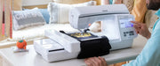 side-angle-view-user-finger-navigating-menu-on-brother-innov-is-nq1700e-embroidery-machine-stitching-gold-crest-design-on-black-fabric